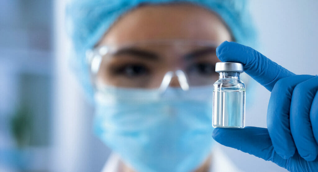 Image of a woman in protective clothing holding a glass vial
