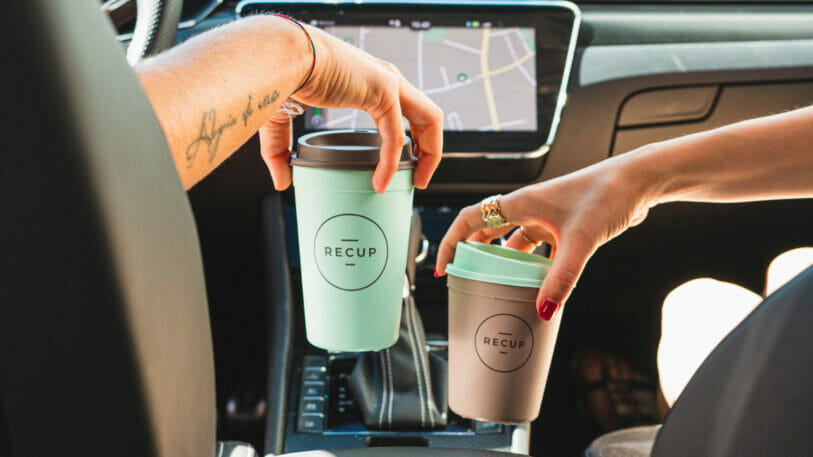 Bild von zwei Personen in einem Auto, die Mehrweg-Kaffeebecher in den Händen halten