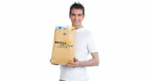 Bild von einem Mann, der eine Papiertüte mit Getränkekartons hält