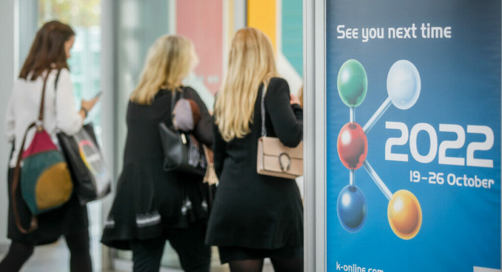 Bild vom Eingang einer Messe mit Menschen und einem Infoschild