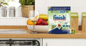 Image of a kitchen isle with an open dishwasher and a packaging of dishwasher tabs