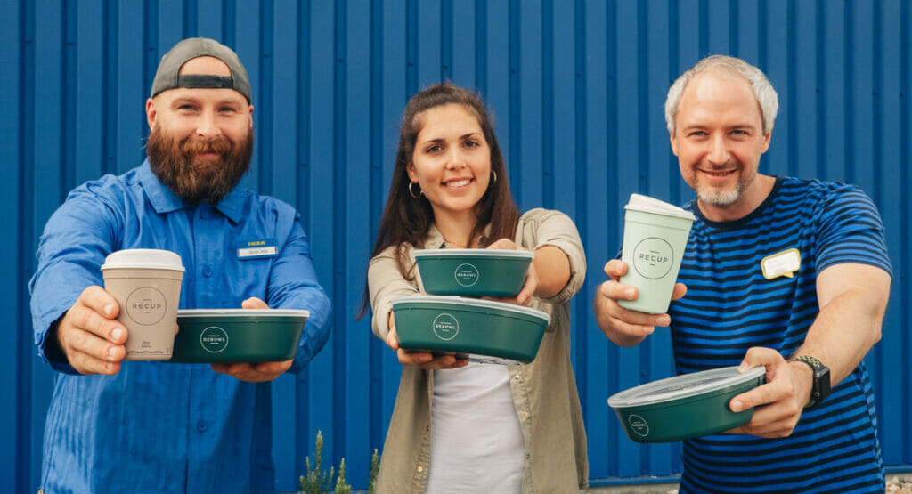 Bild von zwei Männern und einer Frau, die Mehrwegbehälter von Recup halten