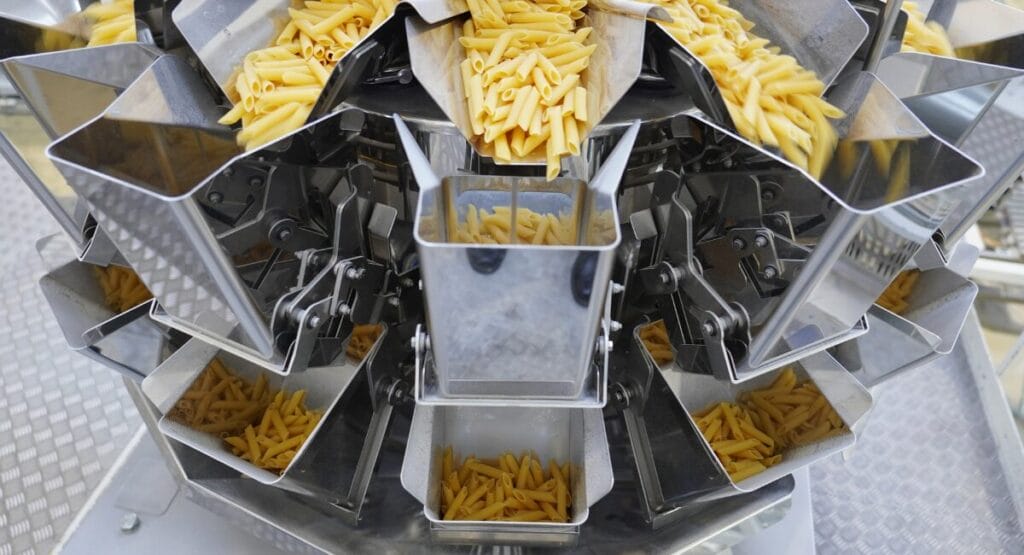The CCW-RVE Enhanced multi-head weighers feed short pasta products into flow-wrapping machines positioned underneath.